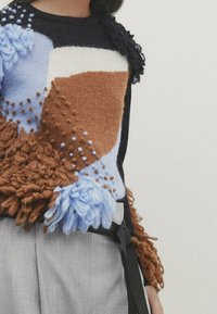 Mehrfarbiger Pullover mit strukturierten braunen, blauen und weißen Flecken. Das Design umfasst flauschige Elemente und einen klassischen Rundhalskragen.