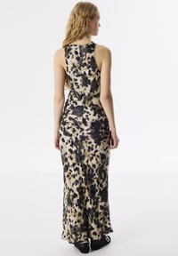 Robe maxi imprimée léopard avec une silhouette ajustée, fabriquée en tissu doux avec des taches beiges, noires et brunes ; fermeture éclair au dos.