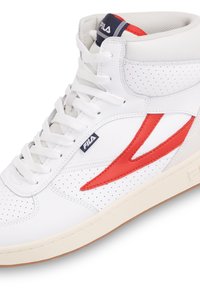 Białe trampki typu high-top z czerwonymi akcentami, perforowaną teksturą i gumową podeszwą. Posiadają logo na języku i bocznej paneli.