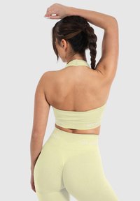 Sujetador deportivo de canalé verde claro y leggings, con un diseño de cuello halter y texto blanco de marca a lo largo de la cinturilla y el dobladillo inferior.