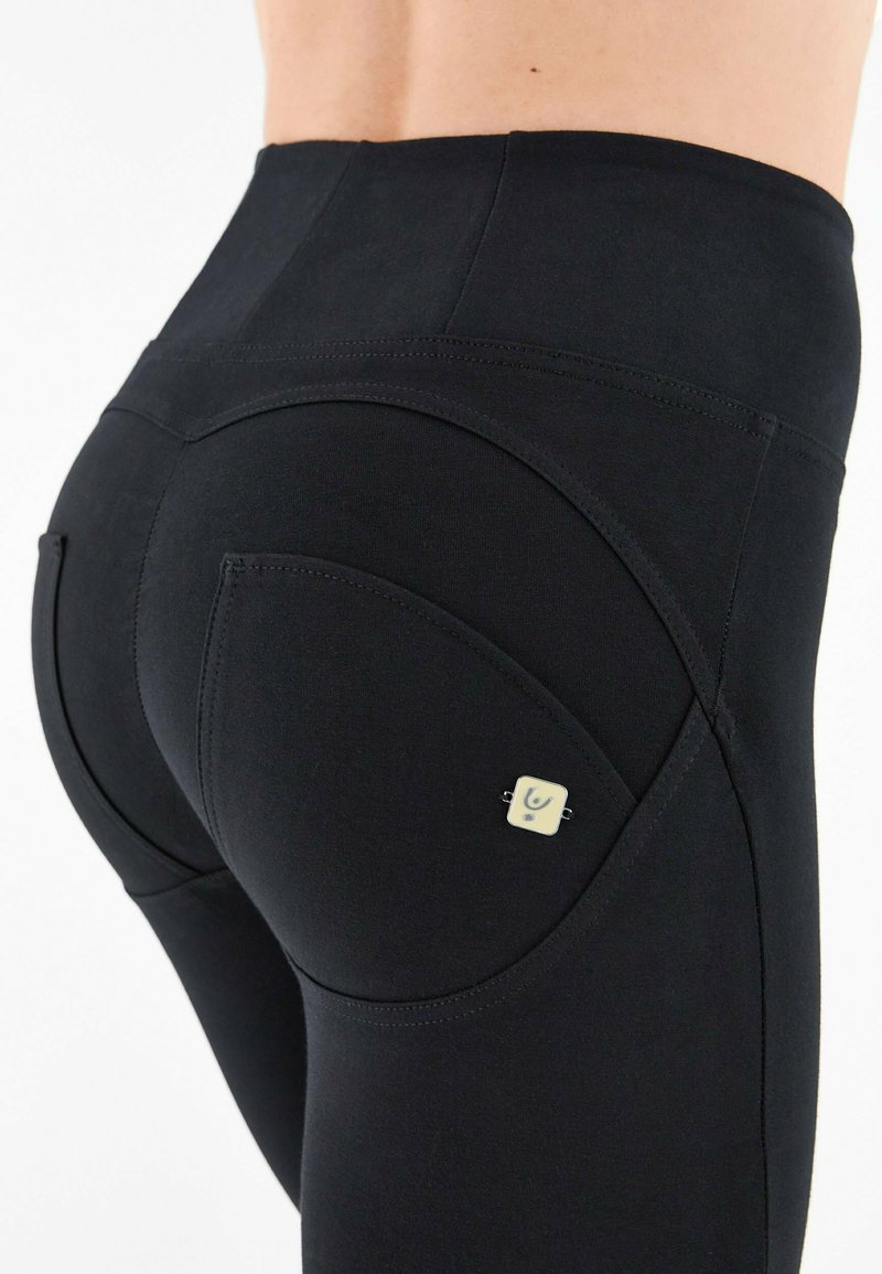 Leggings neri con vita alta, caratterizzati da cuciture curve distintive e da un piccolo marchio nella zona della tasca posteriore. Texture liscia.