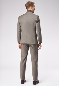 Szary garnitur skrojony na miarę z dopasowaną marynarką i spodniami bez zakładki. Gładka tekstura, subtelny wzór, a także guziki na mankietach.