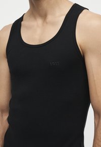 Mannequin masculin portant un débardeur noir ajusté sans manches avec un petit logo BOSS embossé sur la poitrine.