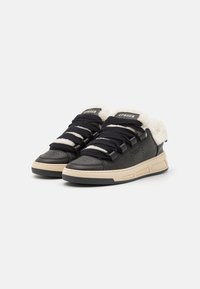 Sorte lærersneakers med beige gummisål, teksturerte snørebånd og en myk hvit fleecekrage. Har merkevare på tungen.
