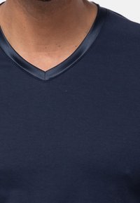 Marineblauwe T-shirt met korte mouwen heeft een V-hals met een gladde, glanzende stofafwerking. Gemaakt van zachte katoen met een eenvoudig, schoon ontwerp.
