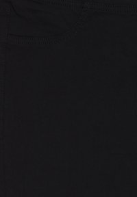 Zbliżenie na czarną tkaninę z widocznymi szwami kieszeni i detalami szwów.