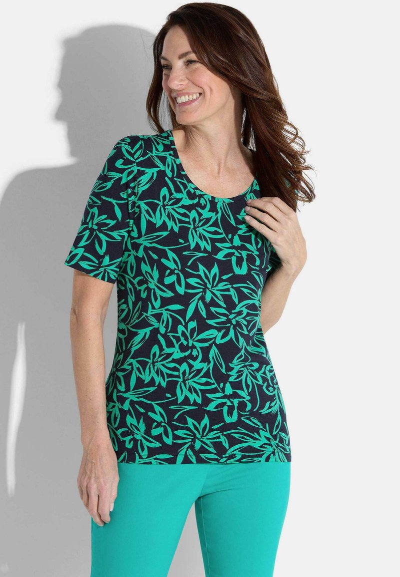 Haut à manches courtes avec une base bleu foncé et un motif floral vert vif. Tissu doux et léger avec un col rond.