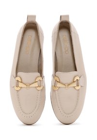Mocassini in pelle beige con punta rotonda, dotati di un accento in catena dorata e dettagli cuciti. Design slip-on con un piccolo tacco.
