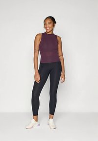 Viininpunainen ribbineuloksinen hihaton toppi yhdistettynä mustiin leggingseihin ja valkoisiin lenkkareihin. Asu on vartalonmyötäinen ja sileän tuntuinen.