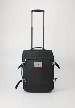 Black travel backpack with telescoping handle, made of durable fabric. Features silver hardware, logo patch, and adjustable side straps.