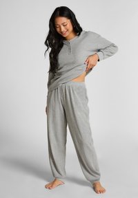 Grå, mjuk pyjamas i tyg med en långärmad henley-topp med knappar och lediga byxor med elastisk midja.
