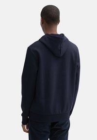 Sudadera de color azul marino hecha de tela suave, con capucha ajustable, puños y dobladillo acanalados. Textura lisa, diseño sencillo y sin logotipos visibles.