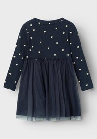 Il vestito lungo a maniche della marina presenta una parte superiore a costine con motivi a cuore dorati e una gonna in tulle. La vita elastica crea un effetto arricciato nella cucitura.