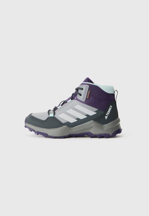 Botte de randonnée mi-haute en gris, violet et teal avec semelle noire, rayures blanches et marquage "TERREX" sur le côté du talon.
