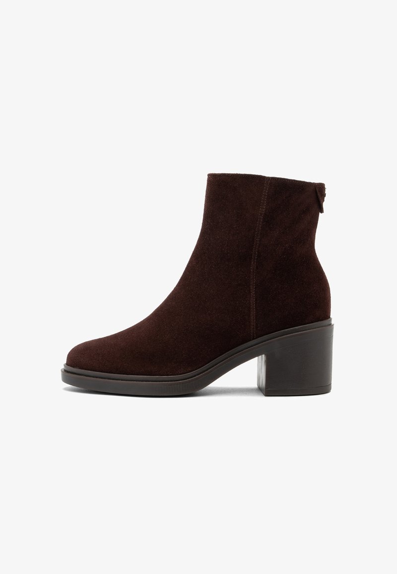 Botine din suede maro, cu toc pătrat și vârf rotunjit. Au un design fără cusături și o bandă la spate pentru a fi ușor de purtat.