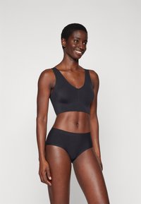 Black seamless bralette with a deep V-neck and wide straps, paired with matching high-waisted briefs, crafted from smooth, stretchy fabric.