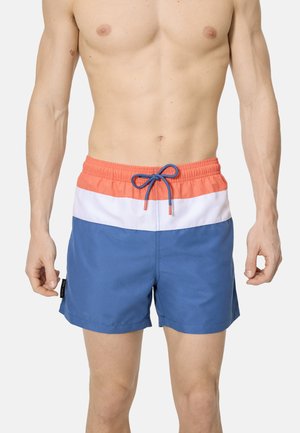 Torso masculino vistiendo pantalones cortos de baño con bloques de color en coral, blanco y azul, con un cordón azul, sobre un fondo liso.