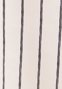 Tissu beige avec des fines rayures verticales noires espacées de manière uniforme et une texture tissée visible.