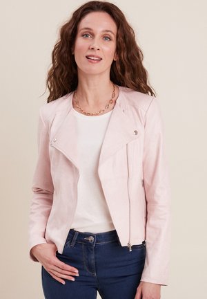 Rosa Faux-Suede-Bikerjacke mit Reißverschluss, mit eingeschnittenem Kragen und silbernen Hardware-Details, kombiniert mit einem weißen Oberteil und blauen Jeans.