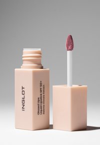 Flüssiger Lippenstift in einem quadratischen, matten beigen Behälter. Enthält einen weißenapplikator mit einer weichen, schrägen Spitze. Das Etikett zeigt schwarzen Text.