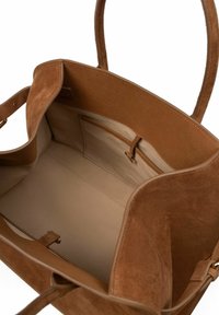 Bruine suede tote bag met beige textielvoering, twee handvatten, een binnenzak en een gladde vorm; geen zichtbare sluitingen.