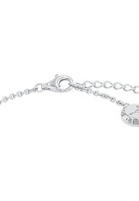 Pulsera de cadena de plata con cierre de langosta, diseño de eslabones planos y un charm redondo con detalles grabados. Textura suave y acabado brillante.
