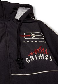 Chaqueta con capucha negra que presenta ribetes blancos, logotipos bordados en rojo y blanco, y un suave forro acolchado. Cordon ajustable en el cuello.