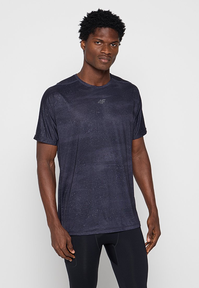 Ciemnoniebieska sportowa koszulka, krótki rękaw, gładka faktura, subtelny wzór, logo 4F na piersi, zestawiona z czarnymi dopasowanymi spodniami.