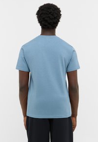 Koszulka z krótkim rękawem, okrągłym dekoltem, wykonana z jasnoniebieskiej bawełny. Prosty design z luźnym krojem i gładką teksturą. Bez dodatkowych detali.