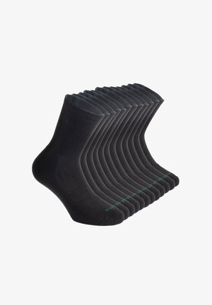 Czarne bawełniane skarpetki ułożone w rzędzie, z prążkowanym wzorem, wzmocnionym palcem oraz zielonym akcentem na podeszwach.