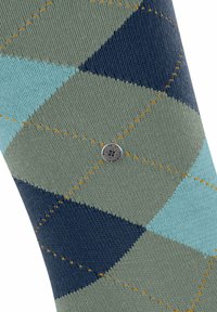 Calzini da uomo a rombi in verde, blu navy e blu con motivi a diamante. Presentano cuciture arancioni a contrasto e un'applicazione di logo metallico.