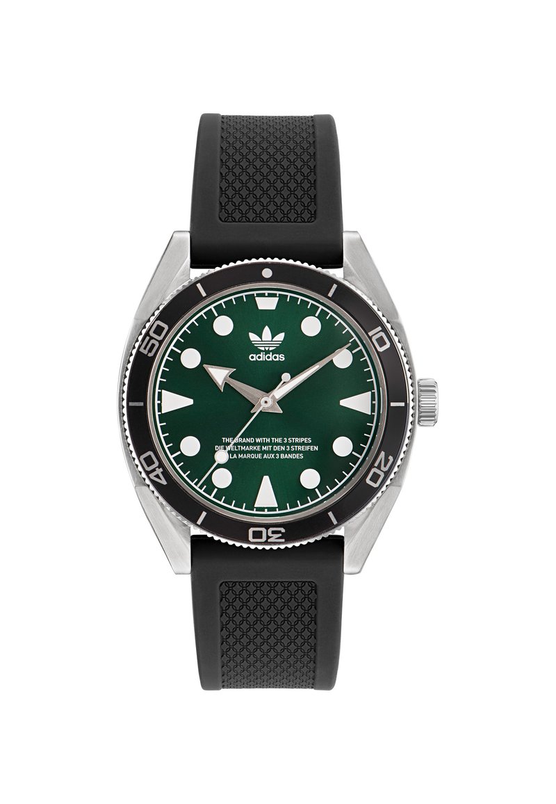 Montre à cadran vert avec boîtier en acier inoxydable argenté et bracelet en caoutchouc noir. Elle présente de grands index horaires blancs et le logo Adidas en trois traits.