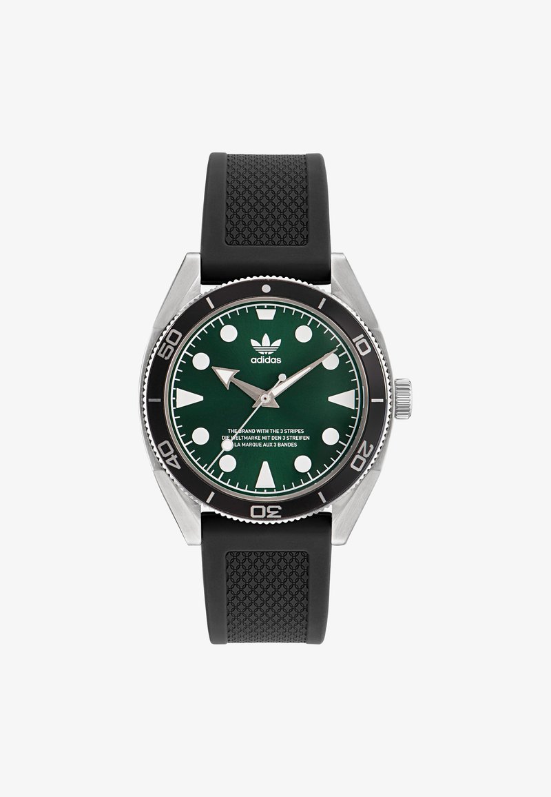 Ceas cu cadran verde, carcasă din oțel inoxidabil argintiu și brățară din cauciuc negru. Dispune de marcatori mari pentru ore de culoare albă și logo-ul Adidas format din trei dungi.