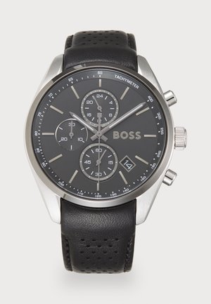 Montre chronographe en acier inoxydable argenté avec un cadran noir, un bracelet en cuir perforé noir et un affichage de date. Elle comprend trois sous-cadrans.