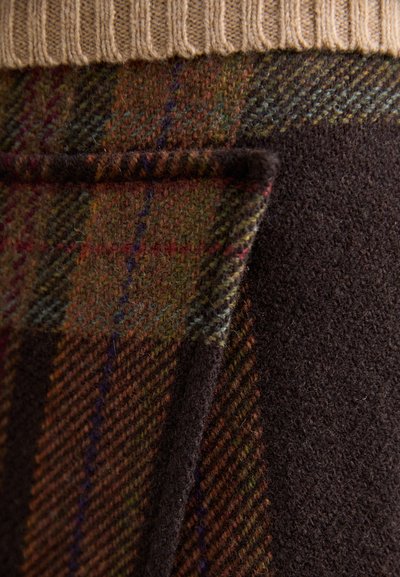 Brown and green plaid fabric with a fuzzy texture, paired with dark brown smooth material, highlighting contrasting patterns and colors.