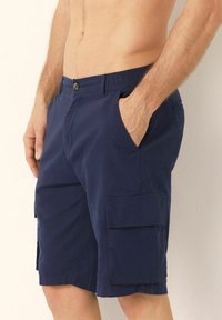 Pantaloni scurți cargo bleumarin cu talie elastică, închidere cu buton, buzunare laterale și buzunare aplicate pe picioare. Realizați dintr-un material ușor.