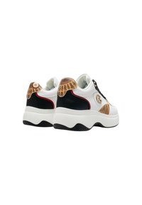 Scarpe da ginnastica bianche con accenti neri, dettagli dorati sulla linguetta e una suola spessa bianca. Presentano un logo rotondo sul lato.