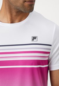 Weißes Sport-T-Shirt mit horizontale Streifen in Pink, Lila und Grau, aus strukturiertem Stoff und mit einem kleinen schwarzen Logo auf der Brust.
