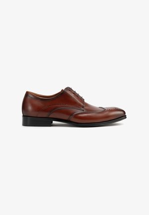 Chaussure habillée pour homme à bout golf en cuir marron avec semelle et lacets noirs, ornée de motifs décoratifs perforés le long des bords.