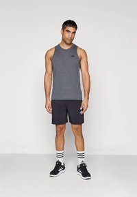 Hall hallataoline sporditopp, mustad lühikesed püksid, mustad tossud ja triibulised sokid, millel on kolm triipu. Topil on Adidas logo.