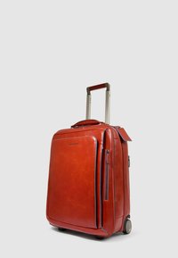 Rode leren koffer met een gladde afwerking, zilverkleurige uitschuifbare handgreep, dubbele wielen en contrasterende blauwe ritssluitingen. Voorzien van een voorvak.