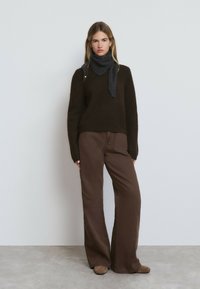 Brauner Strickpullover, grauer Schal und weit geschnittene braune Hose, mit einer weichen Textur und einer lockeren Passform. Einfaches Design ohne Muster.