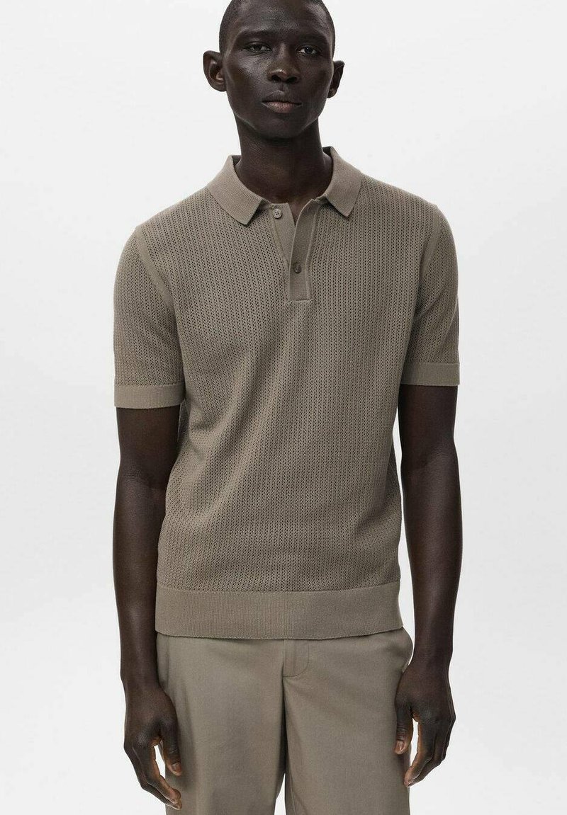 Polo a maniche corte color beige con un design a maglia testurizzata, colletto e polsini a costine. Il tessuto appare morbido e traspirante.