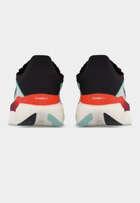 Ζευγάρι πολύχρωμων παπουτσιών για τρέξιμο με μαύρα τακούνια, κόκκινα σημάδια στη μεσαία σόλα και λευκές σόλες, που φαίνεται από πίσω.
