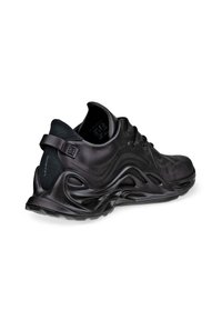 Sneaker nera con una toma superiore liscia e testurizzata, design curvo e suola ondulata distintiva. Dotata di lacci e una linguetta sul tallone per una facile calzata.