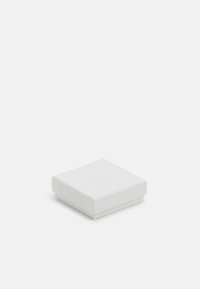 Boîte à bijoux carrée blanche avec une surface texturée et un couvercle lisse, arborant un logo subtil sur le dessus et un mécanisme d'ouverture hermétique.