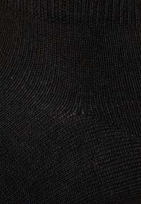 Schwarze Socke mit geripptem Muster, die horizontale Linien aufweist und eine enganliegende Passform bietet. Hergestellt aus einem weichen, dehnbaren Stoff, der für verschiedene Arten von Schuhen geeignet ist.