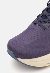Baskets de course violettes avec une tige en tissu texturé et une semelle blanche. Comprend des lacets et un amorti dans la semelle intermédiaire pour le confort. Modèle : GEL-Nimbus 27.