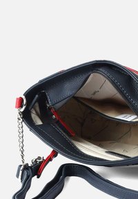 Navy blue leather handbag with a textured finish, red accents, zippered interior pocket, and a removable chain strap. Beige patterned lining.