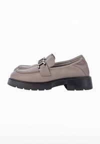Beige leather loafers with a rounded toe, featuring a strap and silver buckle detail, on a textured black platform sole.